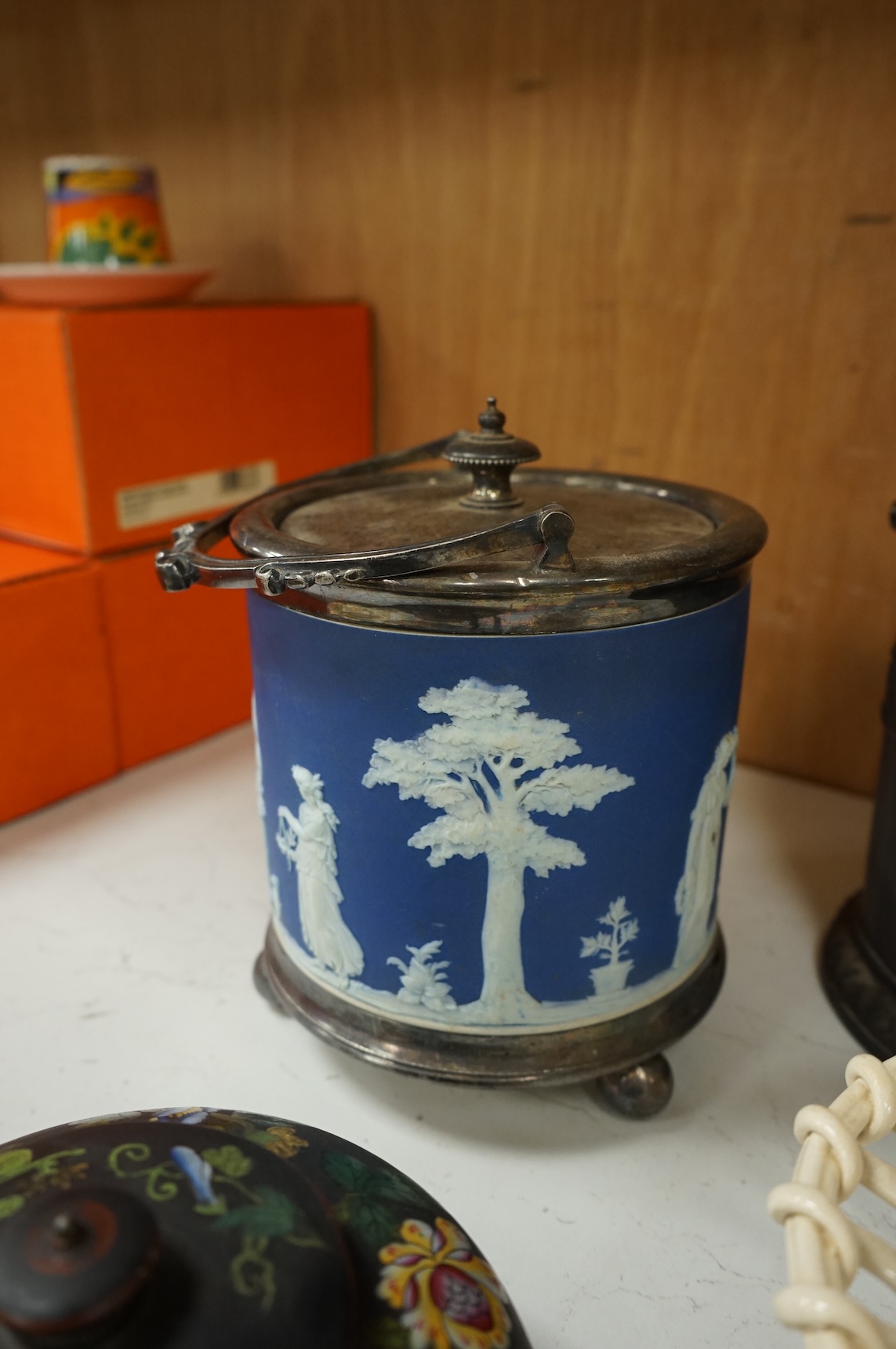 A collection of Wedgwood comprising basalt and jasper biscuit barrels, an enamelled basalt teapot, and a cover and creamware basket, largest 26cm high (4)